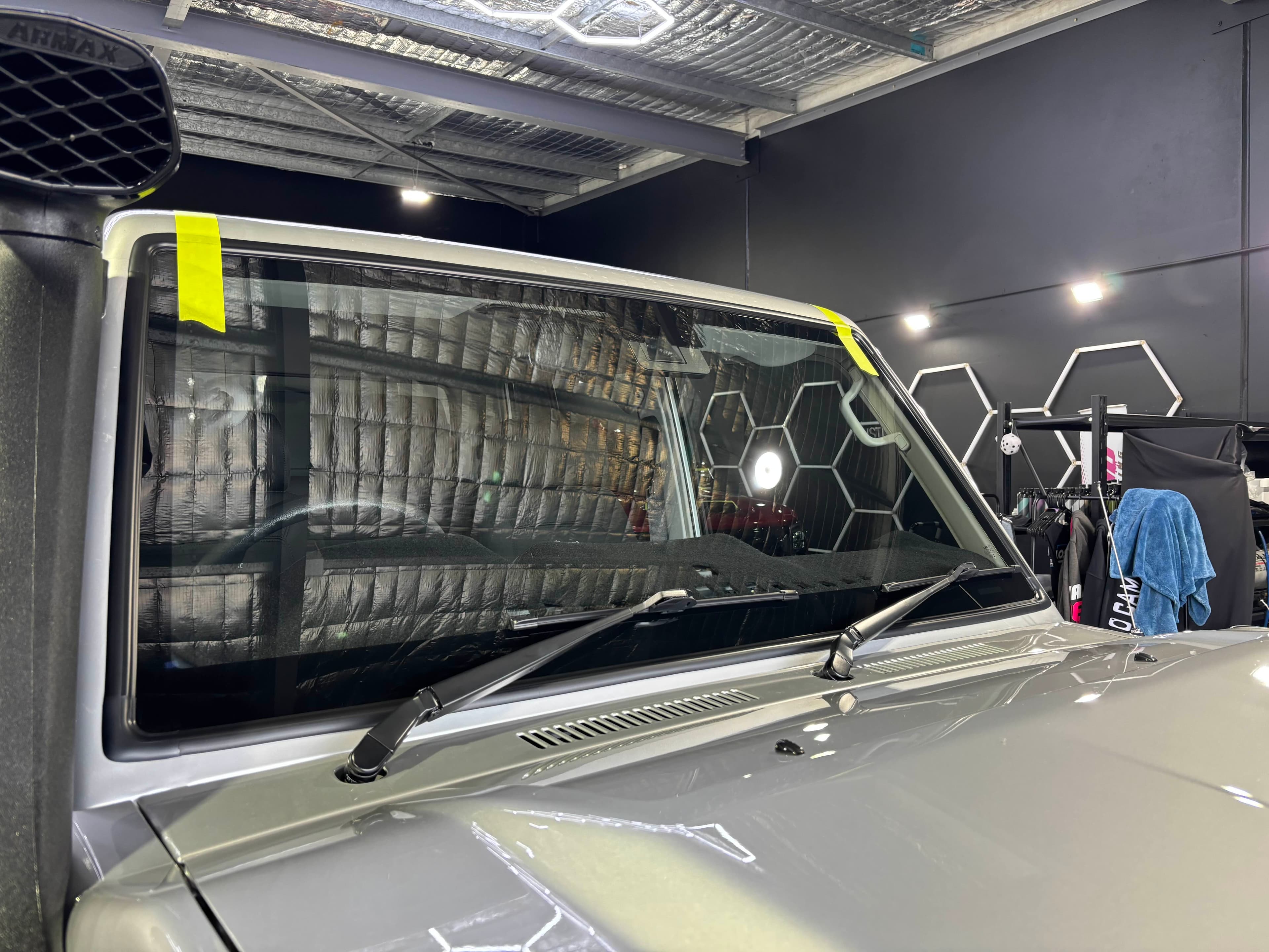 Freshly fitted windscreen held with alignment tape in the workshop